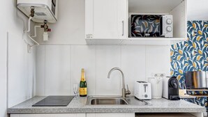 A kitchen with a built-in microwave, a toaster, a coffee maker, and a wine bottle. - TBS 142 - Cosy Studio at the Gates of Paris (Paris)