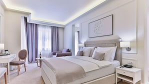 Une chambre d’hôtel avec un grand lit, un bureau, une chaise, une petite table et une table de chevet avec un téléphone.