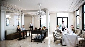 Un vaste espace de restauration d’hôtel, aménagé avec un buffet, un lustre et de grandes fenêtres offrant une vue panoramique.