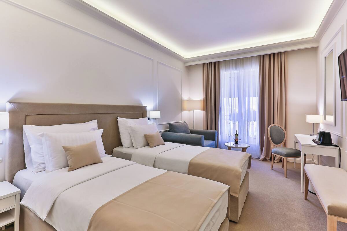 Ein Hotelzimmer mit zwei Betten, einem Schreibtisch, einem Stuhl und einem Fernseher.