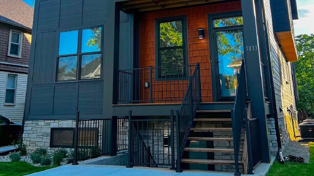 A two-story modern house with a prominent red roof, large windows, and a visible address number 1033. - Newly-built modern farmhouse condo available in Grosse Pointe Park! (Grosse Pointe Park)