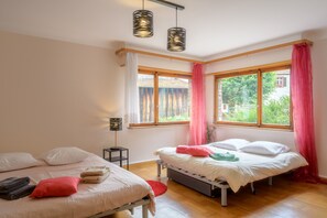 Un dormitorio con dos camas, una mesita y una ventana con cortinas.