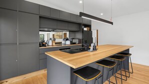Cozinha moderna com ilha central, banquetas e vista para a sala de jantar.