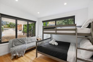 A bunk bed with a view of a garden through large windows.