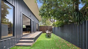 Uma casa moderna com varanda, espaço de jantar e quintal cercado.