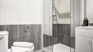 A modern bathroom with a glass-enclosed shower, a toilet, and a sink with toiletries. - TheBlueStay 134 - Cozy Apartment in Bagnolet (Paris)