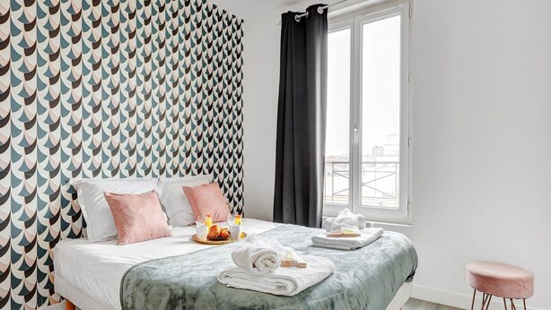 A neatly made bed with a green blanket, two pink pillows, and a breakfast tray with croissants and juice. - TheBlueStay 134 - Cozy Apartment in Bagnolet (Paris)