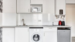 A compact kitchen with a dishwasher, washing machine, microwave, and a coffee maker. - TheBlueStay 134 - Cozy Apartment in Bagnolet (Paris)