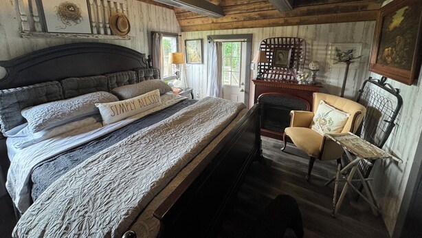 Een rustieke slaapkamer met een groot bed, een houten stoel en een open haard.