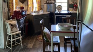Een landelijke keuken met houten wanden, een houten plafond, een rode magnetron, een spoelbak, een fornuis en een eettafel met stoelen.