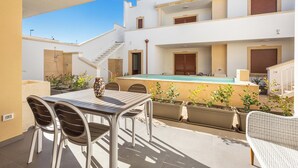 Une terrasse extérieure moderne, dotée d’une piscine, de coins salon et de plantes en pot.