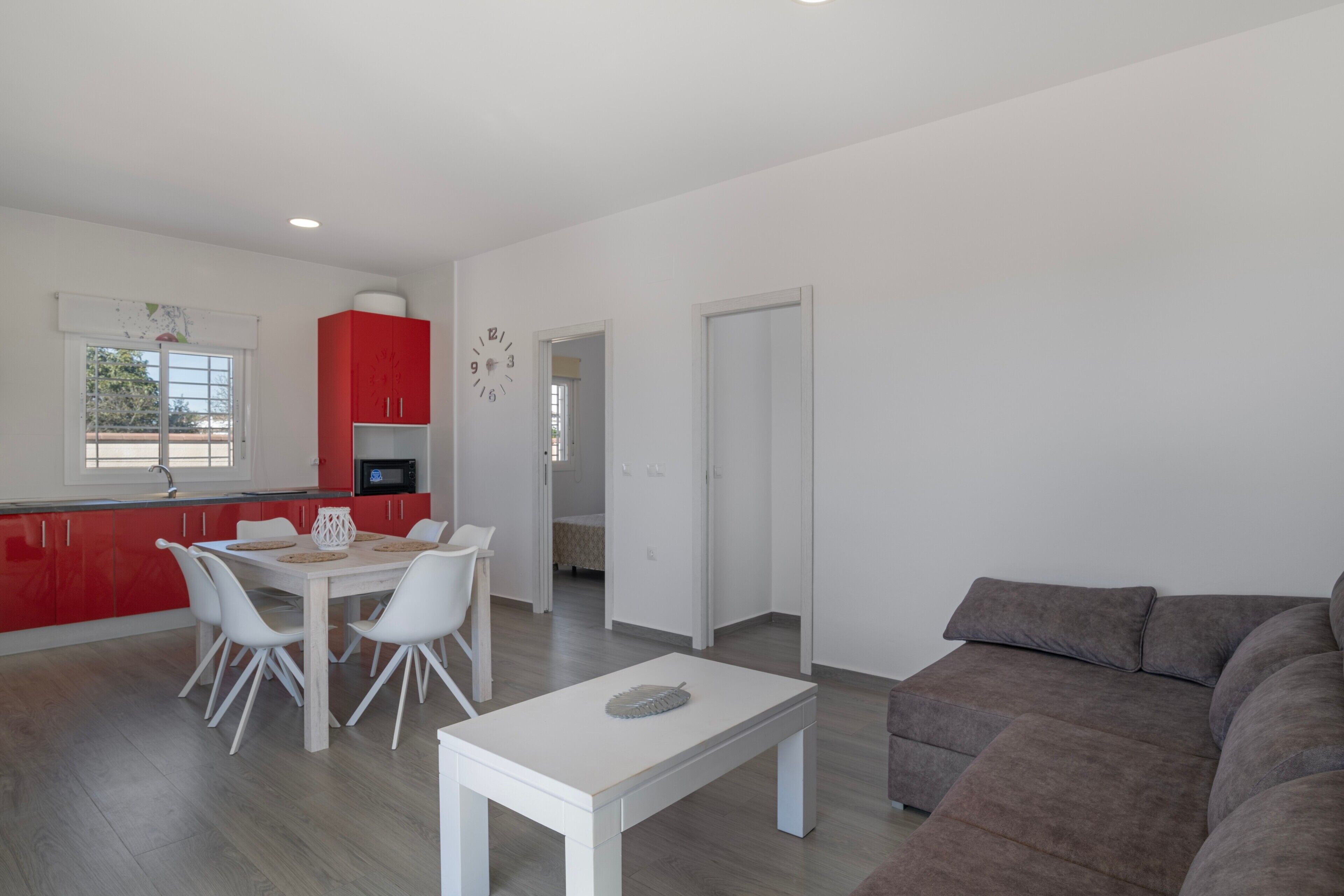 Un soggiorno moderno con zona pranzo, cucina e un grande divano grigio.