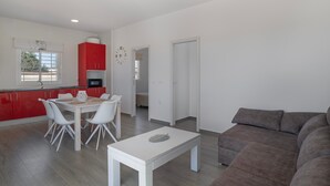 A modern living space with a dining area, kitchen, and a large gray sofa.