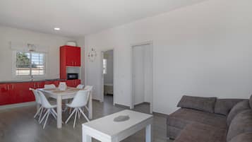 Un soggiorno moderno con zona pranzo, cucina e un grande divano grigio.