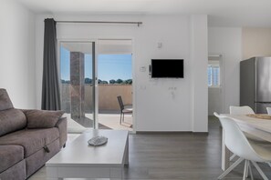 A modern living room with a sofa, a coffee table, a TV mounted on the wall, and a sliding glass door leading to an outdoor area. - Holiday Home 'El Descanso' with Private Pool, Wi-Fi and Air Conditioning (Conil de la Frontera)