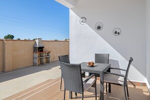 An outdoor patio with a table and chairs, a grill, and decorative wall stickers. - Holiday Home 'El Descanso' with Private Pool, Wi-Fi and Air Conditioning (Conil de la Frontera)