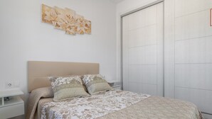 A bedroom with a bed, a nightstand, a wall-mounted artwork, and a sliding door.