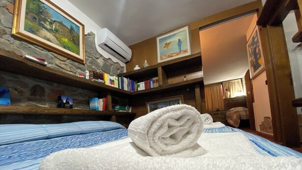 Une chambre d’hôtel avec un lit, une serviette blanche roulée, une cheminée en pierre et une bibliothèque remplie de livres.