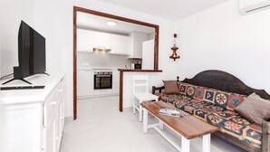 A compact living space with a kitchenette, a sofa, a TV, and a dining table.