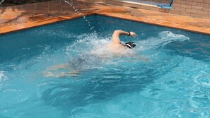 Una piscina al aire libre, sombrillas, sillones reclinables de piscina