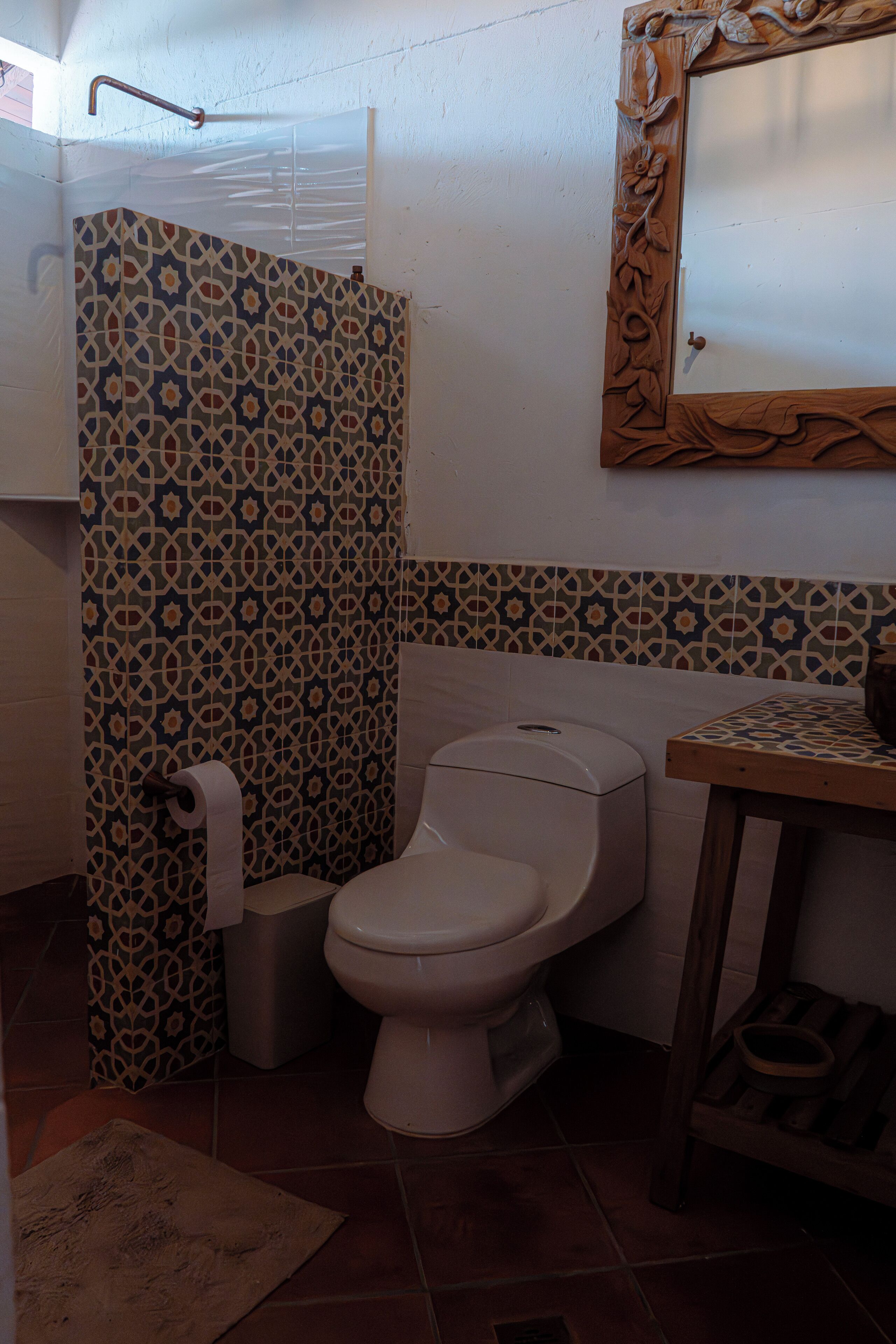A bathroom with patterned tiles, a toilet, a shower, and a wooden vanity.
