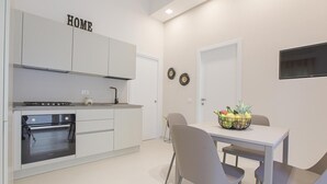 Uma cozinha moderna com armários brancos, forno embutido e uma área de refeições com mesa e cadeiras.