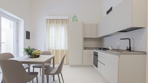 Cozinha moderna com área de refeições, armários brancos e uma janela com cortinas.