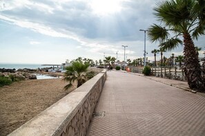 A paved walkway beside a beach with palm trees and a stone wall. - Apartment 'Casa Ancora' with Private Terrace, Wi-Fi and Air Conditioning (San Leone)