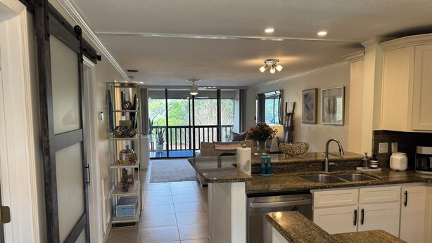 A modern kitchen with granite countertops, stainless steel appliances, and a view to the outside. - Modern 2 Bedroom Condo in Prime Gulf-Front Community with Pool, Wifi, AC & More (Tarpon Springs)