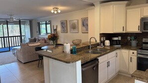A modern kitchen with white cabinets, a granite countertop, and stainless steel appliances. - Modern 2 Bedroom Condo in Prime Gulf-Front Community with Pool, Wifi, AC & More (Tarpon Springs)