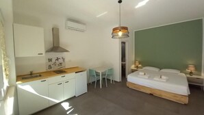 Una habitación de hotel compacta con kitchenette, una cama, comedor y baño.