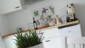 Una cocina con una mesa de madera, un armario blanco y una planta en maceta con una cara dibujada.