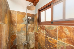A shower with a rain shower head, a handheld showerhead, and a wall-mounted control.