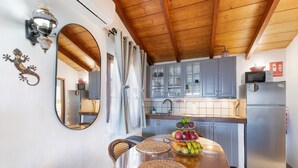 A kitchen with a wooden ceiling, a dining table with woven placemats, a fruit bowl, and a refrigerator. - Holiday Home 'El Perenquén' with Mountain View, Wi-Fi and Air Conditioning (Los Llanos de Aridane)