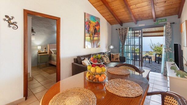 A dining area with a wooden table, woven placemats, and a fruit display. - Holiday Home 'El Perenquén' with Mountain View, Wi-Fi and Air Conditioning (Los Llanos de Aridane)