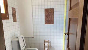 Un baño con inodoro, bidé y un estante de madera tipo escalera.