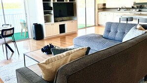 A living room with a grey sofa, a coffee table, and a TV on a white entertainment unit.
