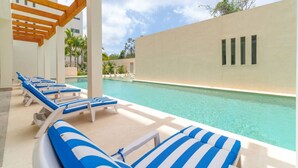 A poolside area with lounge chairs and a clear view of the pool. - 2 BD Suite w/ Balcony, Gym + Rooftop Pool (Playa del Carmen)