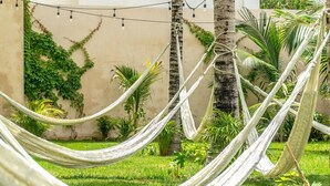 A hammock set up in a lush garden with palm trees and greenery. - 2 BD Suite w/ Balcony, Gym + Rooftop Pool (Playa del Carmen)
