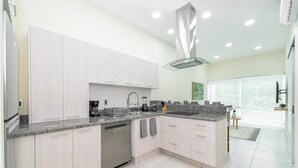 A modern kitchen with light wood cabinets, granite countertops, and a built-in dishwasher. - 2 BD Suite w/ Balcony, Gym + Rooftop Pool (Playa del Carmen)