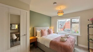 Un dormitorio con cama, mesita de noche y ventana con vista a edificios.
