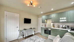 Un espacio habitable compacto con comedor, kitchenette y cama con un tapete mullido.