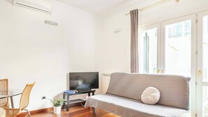 A modern living room with a sofa, TV, and dining area.