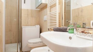 A bathroom with a toilet, a shower, and a sink.