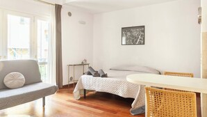 A bedroom with a bed, a chair, a small table, and a picture on the wall.