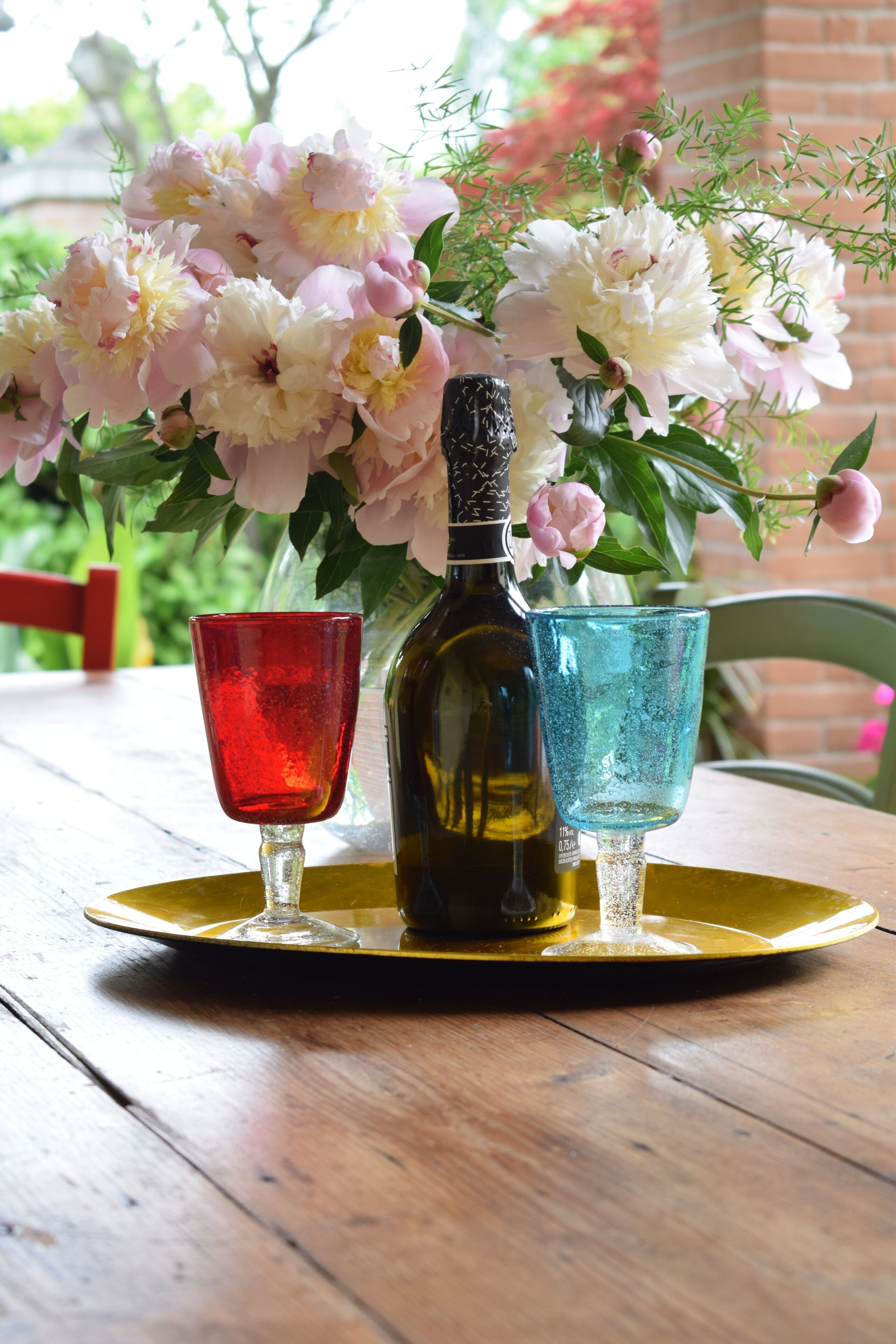 A table with a bottle of wine, two glasses, and a bouquet of flowers.