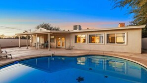 Una casa moderna con piscina, terraza cubierta y garaje.