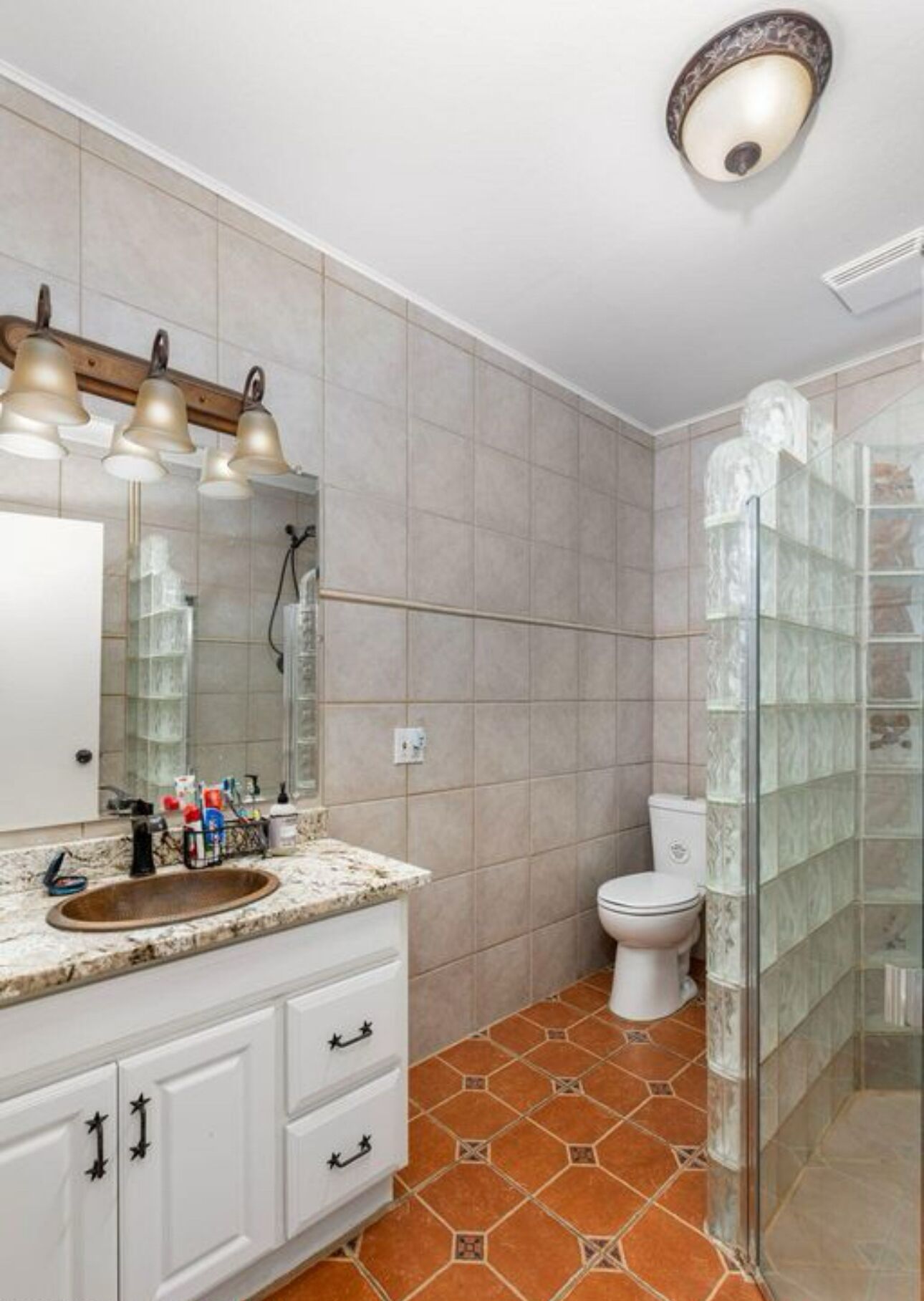Un baño con lavamanos, espejo e inodoro.
