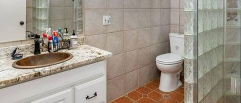 Un baño con lavamanos, espejo e inodoro.
