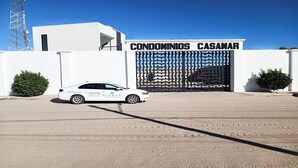 A white car parked in front of a building with a gated entrance labeled "CONDOMINIOS CASAMAR". - Condo Casamar 3 by Kivoya (Puerto Peñasco)